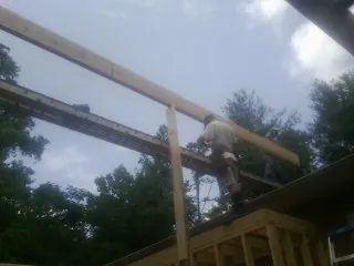 Carpenter setting a ridge beam over a new addition frame — Ice Dam Removal by Roofing Brothers in Ashburn