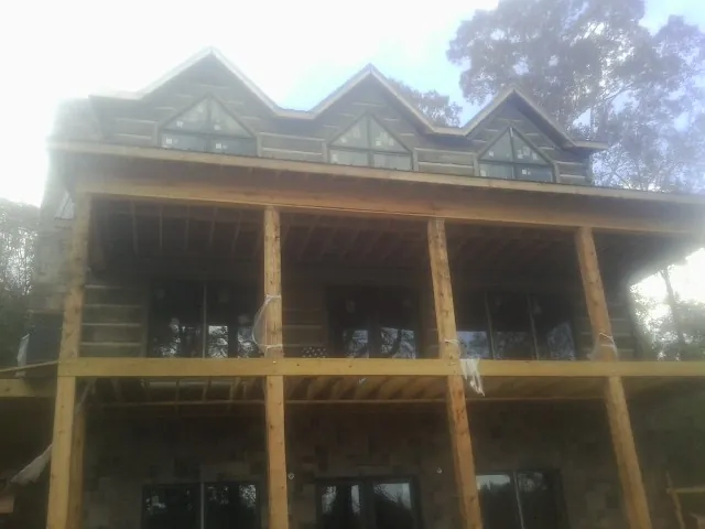 Dormers and porch framing on a large log home under construction — Roof Coating work by our crew in Ashburn