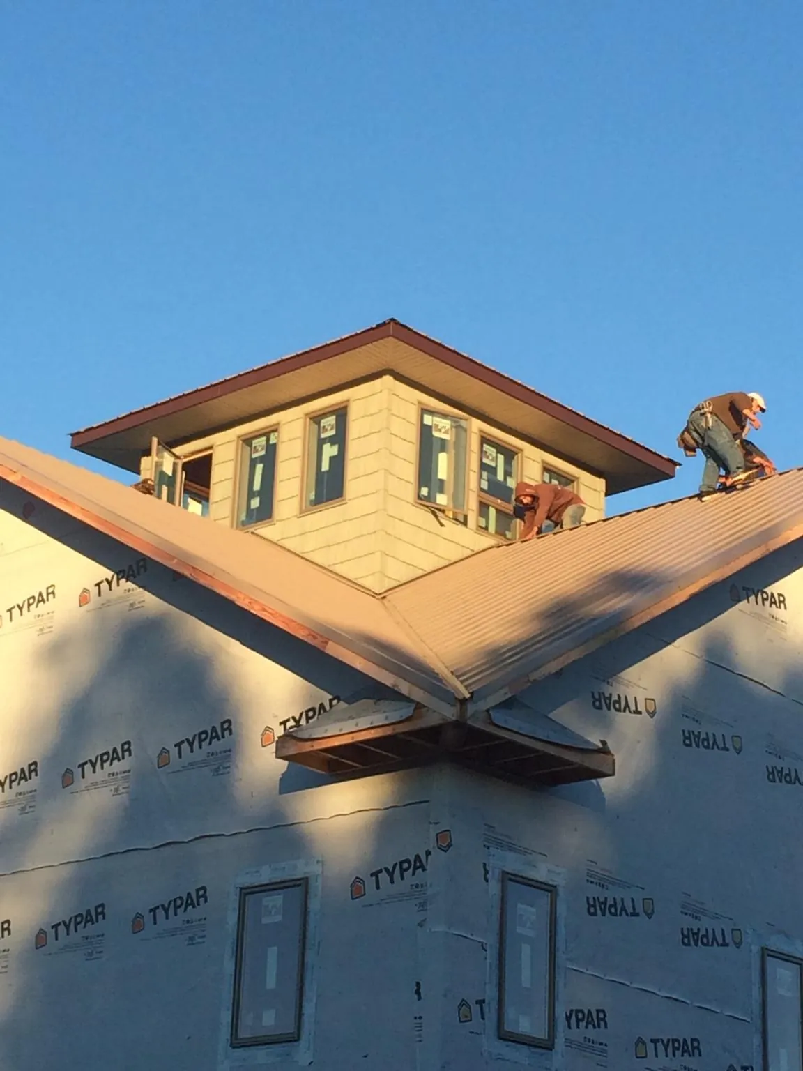 Roofers working around a rooftop cupola on a new metal roof at sunset — Roof Waterproofing in Ashburn by Roofing Brothers